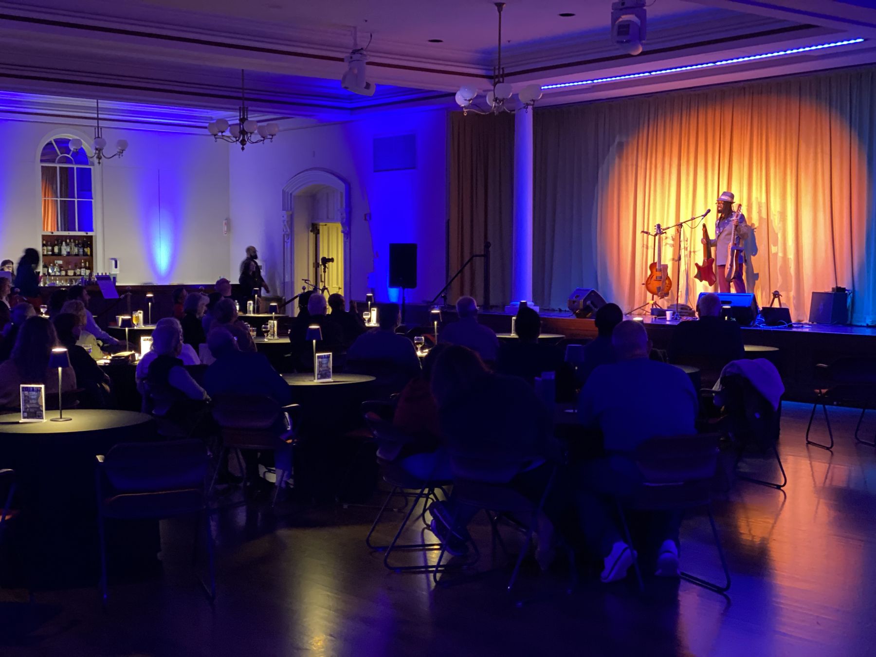 The room on show night: audience at candlelit tables facing a spotlit stage